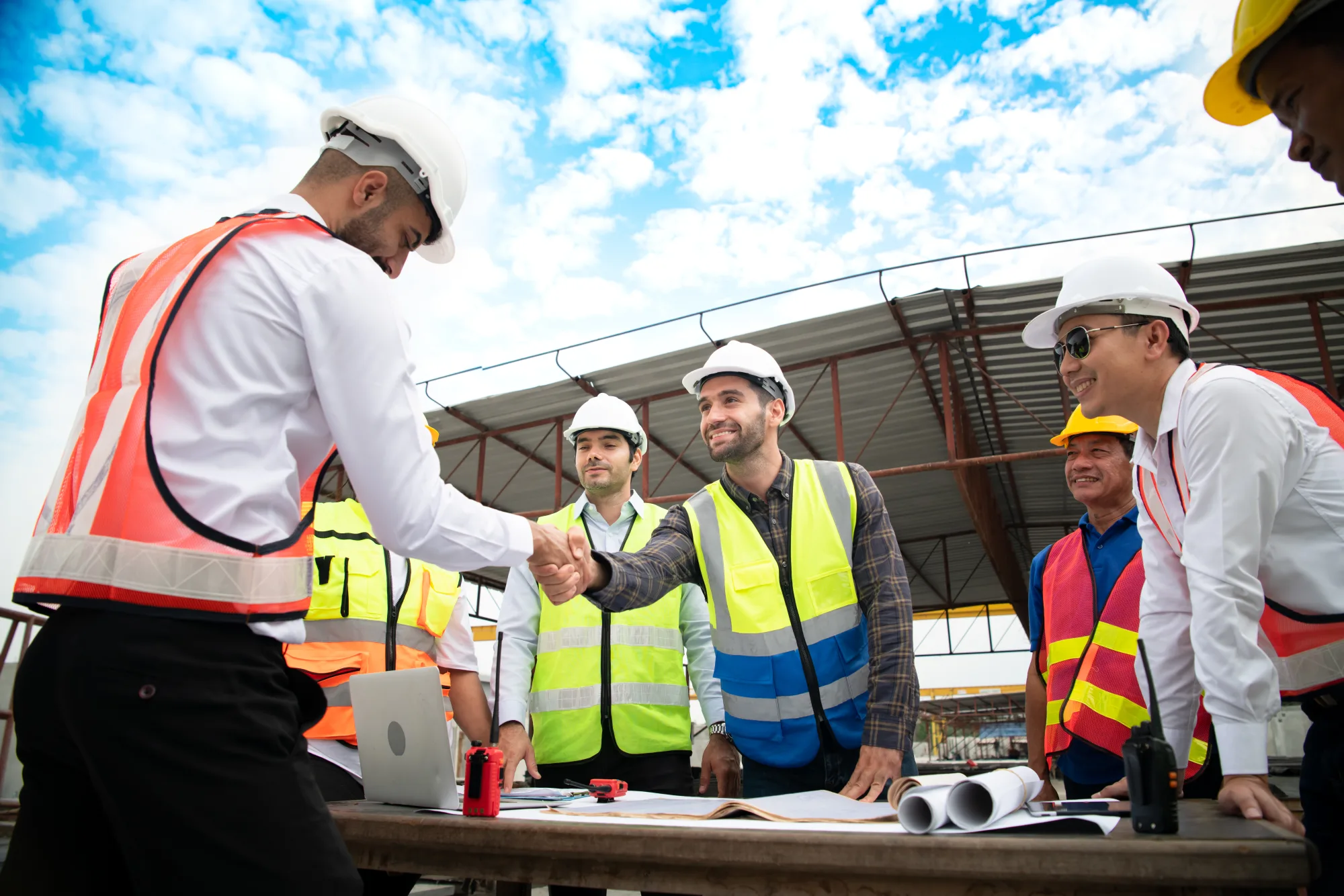 A subcontractor and a general contractor shaking hands over a project model