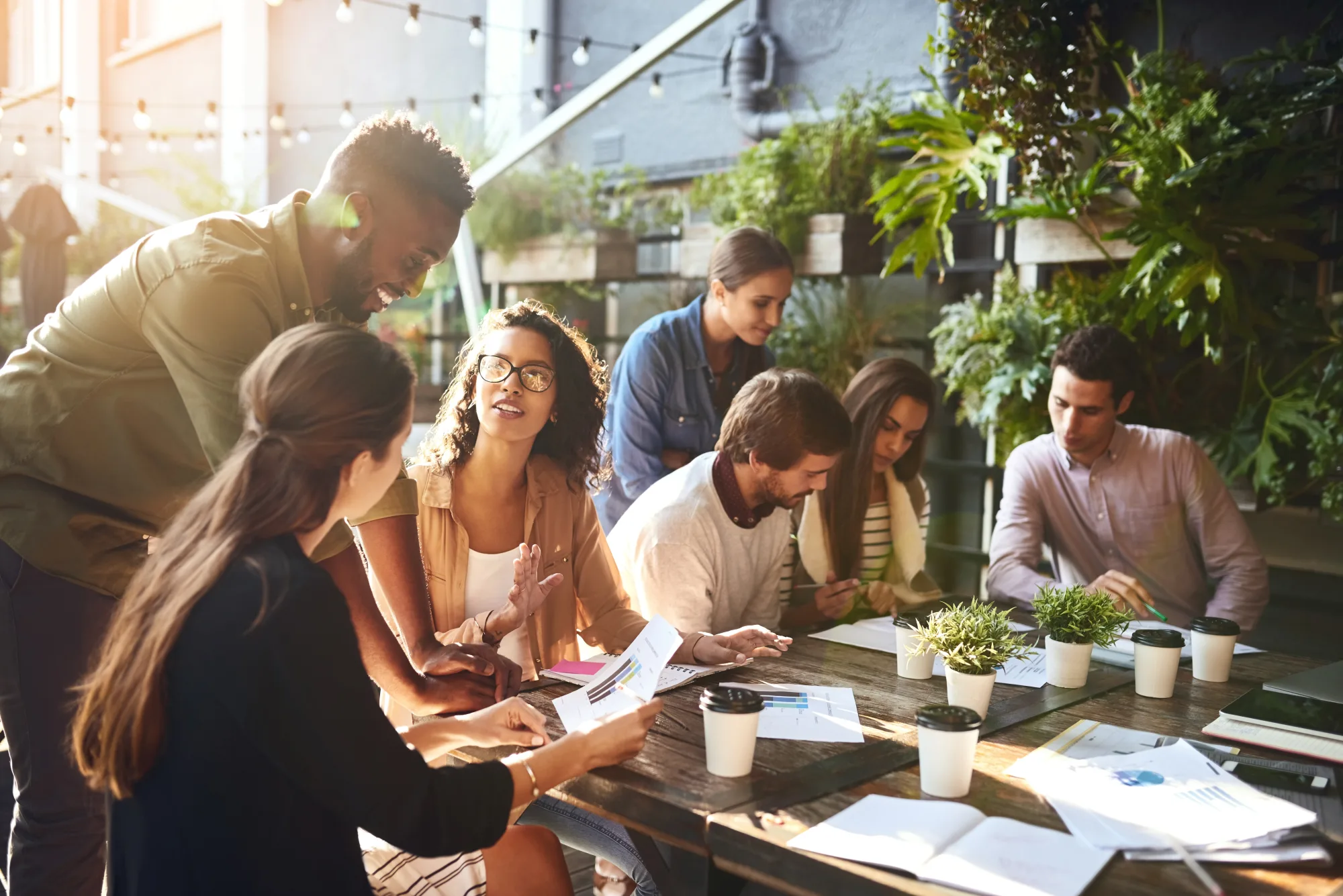 A team collaborating over documents at an outdoor rooftop meeting