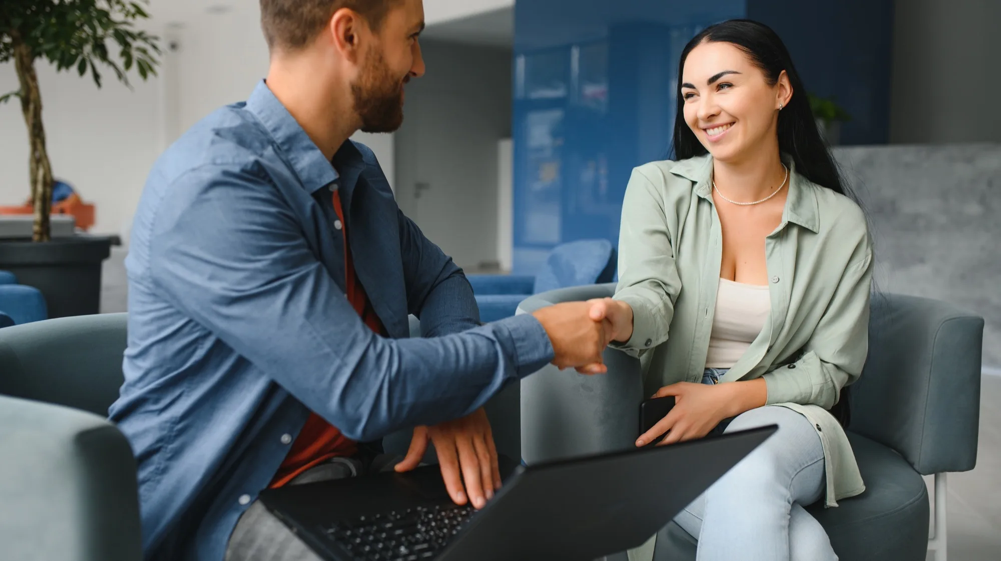 Two business partners shaking hands in an office lobby